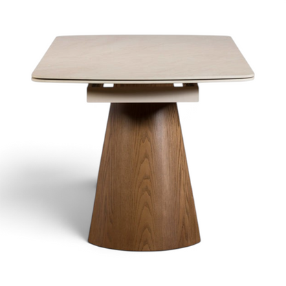 Pieces For Places extending dining table with a cream sintered stone top and a conical ash-veneered pedestal base.