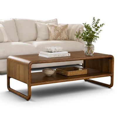 Pieces For Places Saturn coffee table in warm mango wood with rounded edges and a lower storage shelf in a living room