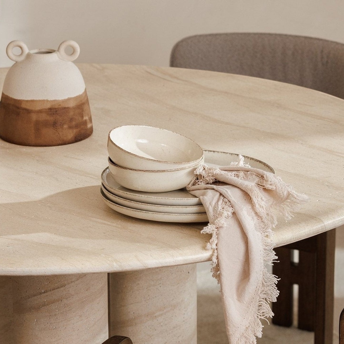 Pieces For Places Ida 120cm round dining table with travertine finish, column legs, and minimalist table setting.