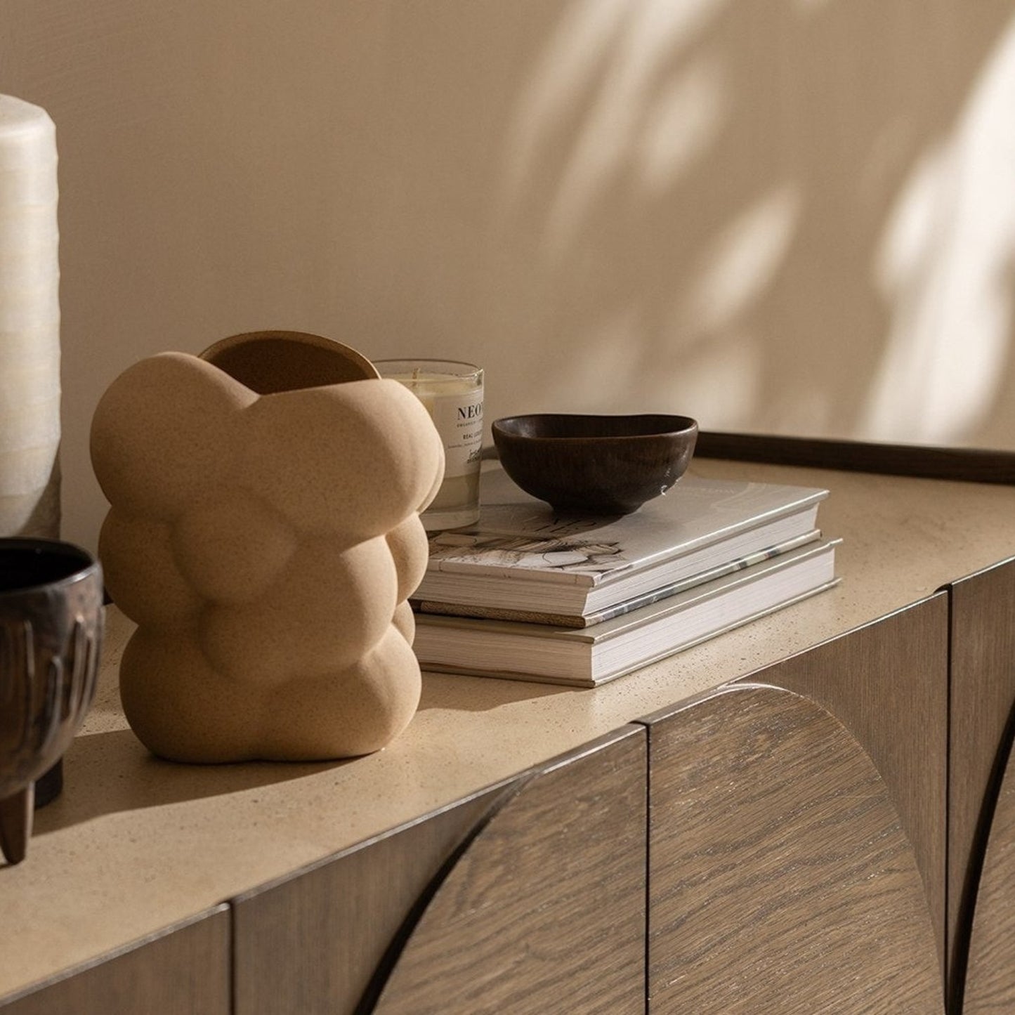 Pieces For Places Ida wide sideboard with walnut oak finish and travertine stone top, styled with decorative vases.