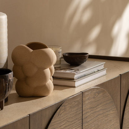 Pieces For Places Ida wide sideboard with walnut oak finish and travertine stone top, styled with decorative vases.
