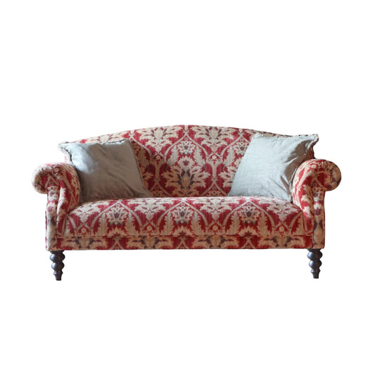 Pieces For Places Tallis Petit Sofa in red damask fabric with rolled arms and two light grey scatter cushions on dark wood legs.